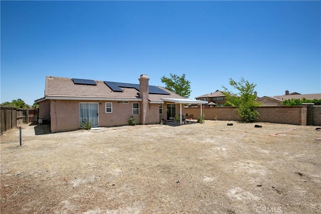 44303 Freer Way, Lancaster, CA 93536 - rear view of house with solar panels, a fenced backyard, stucco siding, a tile roof, and a chimney