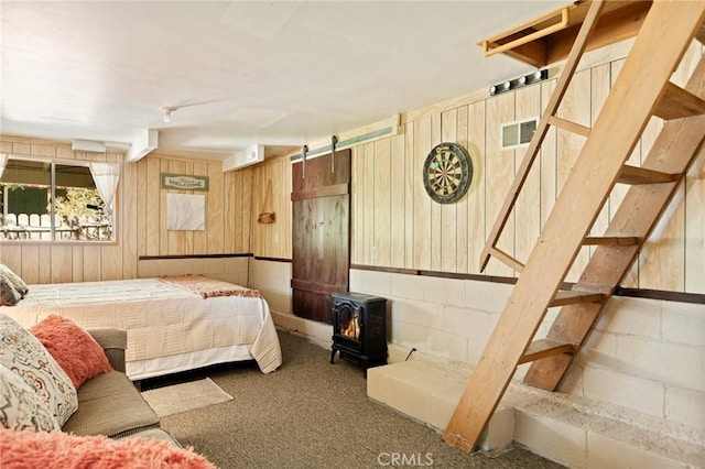 32953 Juniper Ln, Green Valley Lake, CA 92341 - carpeted bedroom featuring wood walls, a wood stove, and concrete block wall