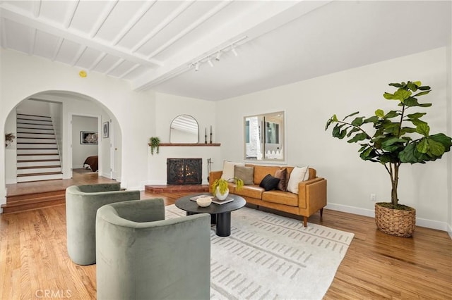 4131 Edgehill Dr, Los Angeles, CA 90008 - living room featuring arched walkways, light wood finished floors, rail lighting, stairway, and beamed ceiling