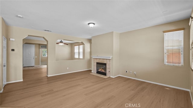 3360 Hammock St, Perris, CA 92571 - unfurnished living room with arched walkways, light wood-type flooring, ceiling fan, and a tiled fireplace