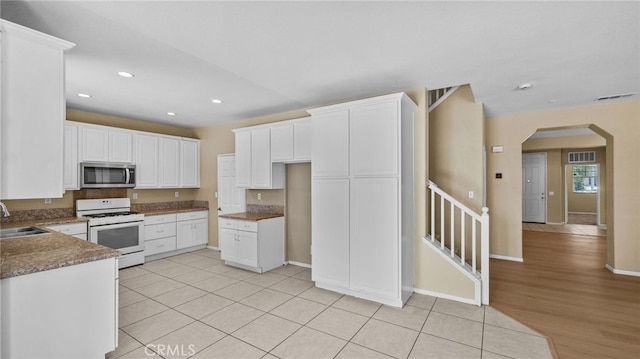3360 Hammock St, Perris, CA 92571 - kitchen featuring stainless steel microwave, white gas range oven, arched walkways, white cabinets, and recessed lighting