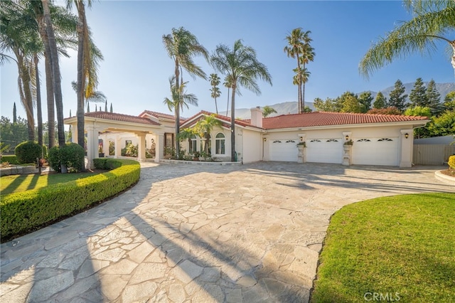 275 E 24th St, Upland, CA 91784 - mediterranean / spanish home featuring curved driveway, stucco siding, a tile roof, an attached garage, and a chimney