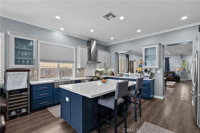 28518 High Ridge Dr, Saugus, CA 91390 - kitchen featuring wall chimney exhaust hood, blue cabinetry, a center island, plenty of natural light, and crown molding