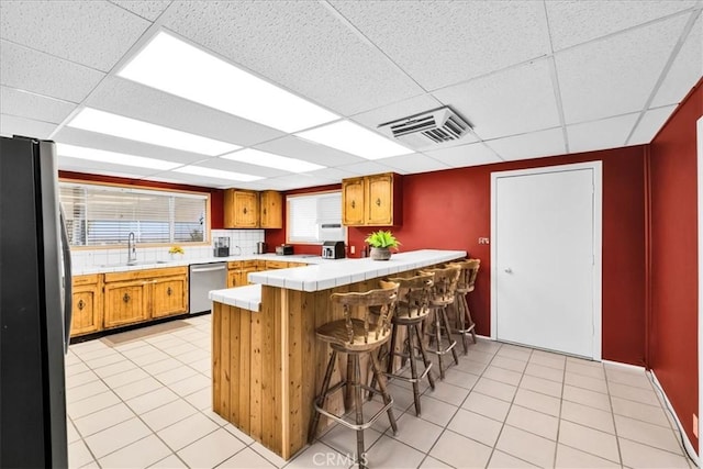 1638 Hales Dr Unit 29, Palms, CA 92277 - kitchen with appliances with stainless steel finishes, a peninsula, a drop ceiling, a breakfast bar, and tile countertops