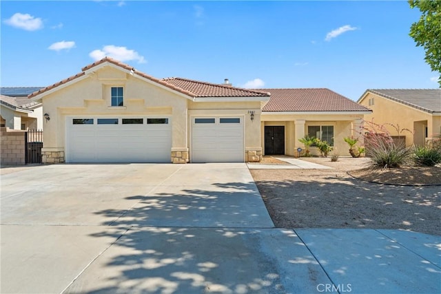 2041 Kalliope Ave, Lancaster, CA 93536 - mediterranean / spanish house featuring an attached garage, stucco siding, a tile roof, concrete driveway, and stone siding