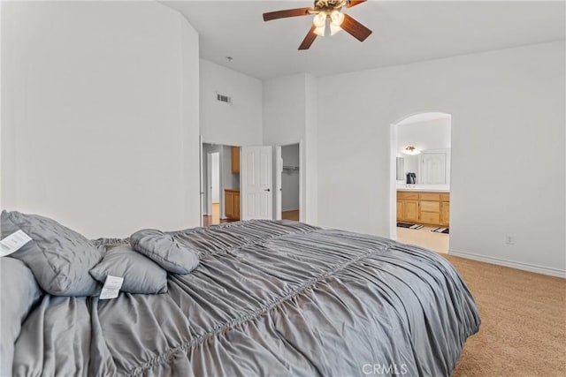 2041 Kalliope Ave, Lancaster, CA 93536 - bedroom featuring light carpet, arched walkways, connected bathroom, and ceiling fan