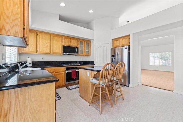 2041 Kalliope Ave, Lancaster, CA 93536 - kitchen with appliances with stainless steel finishes, dark countertops, a breakfast bar, light colored carpet, and recessed lighting