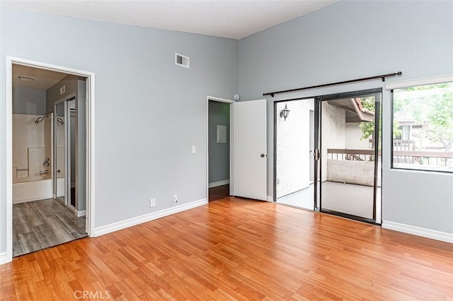 13100 Creek View Dr Unit 204, Garden Grove, CA 92844 - unfurnished bedroom featuring access to outside, light wood-type flooring, connected bathroom, and a high ceiling