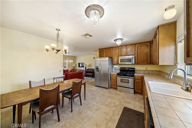 58706 Buena Vista Dr, Yucca Valley, CA 92284 - kitchen featuring appliances with stainless steel finishes, tile countertops, a chandelier, and brown cabinets