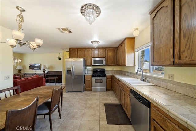 58706 Buena Vista Dr, Yucca Valley, CA 92284 - kitchen with appliances with stainless steel finishes, a chandelier, tile counters, and brown cabinets