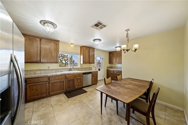 58706 Buena Vista Dr, Yucca Valley, CA 92284 - kitchen featuring appliances with stainless steel finishes, a chandelier, light tile patterned flooring, and brown cabinetry