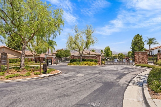 9116 Pinyon Point Ct, Corona, CA 92883 - view of asphalt street featuring a gate, a mountain view, curbs, and a gated entry