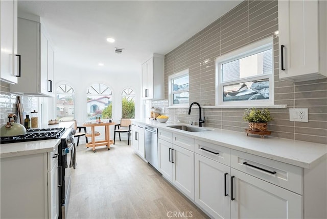 1818 W 79th St, Los Angeles, CA 90047 - kitchen featuring stainless steel appliances, decorative backsplash, white cabinets, light wood-style floors, and light stone counters