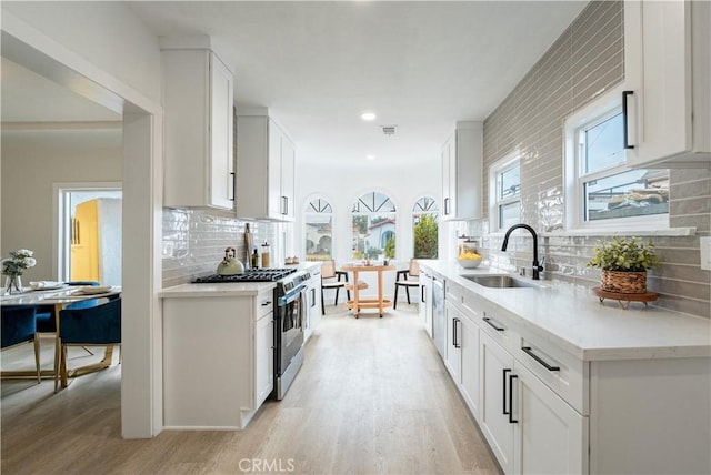 1818 W 79th St, Los Angeles, CA 90047 - kitchen featuring gas stove, backsplash, light wood-style flooring, white cabinetry, and recessed lighting