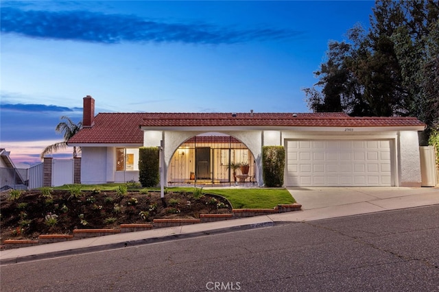 27403 Garza Dr, Saugus, CA 91350 - mediterranean / spanish home featuring concrete driveway, a garage, stucco siding, a tile roof, and a chimney