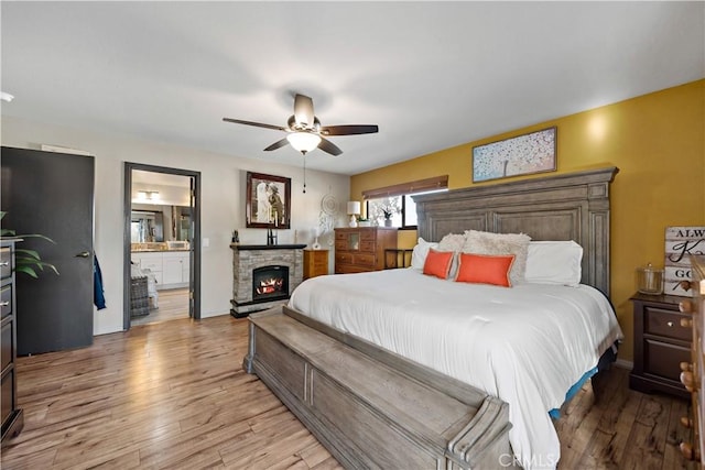 30451 San Pasqual Rd, Temecula, CA 92591 - bedroom featuring light wood-style floors, a stone fireplace, ensuite bathroom, and a ceiling fan