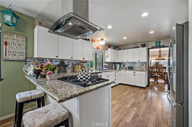 30451 San Pasqual Rd, Temecula, CA 92591 - kitchen with island range hood, freestanding refrigerator, black gas stovetop, a peninsula, and light wood-type flooring