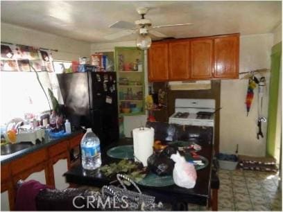 7223 Holmes Ave, Los Angeles, CA 90001 - kitchen with under cabinet range hood, freestanding refrigerator, brown cabinetry, ceiling fan, and white stove