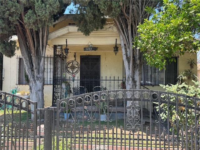 7223 Holmes Ave, Los Angeles, CA 90001 - view of front facade with stucco siding, a gate, a fenced front yard, and covered porch