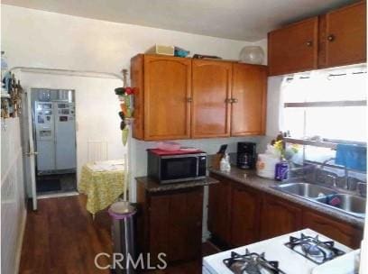 7223 Holmes Ave, Los Angeles, CA 90001 - kitchen with stainless steel microwave, brown cabinets, range, and dark wood finished floors
