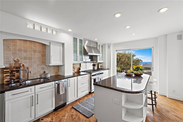 970 Quivera St, Laguna Beach, CA 92651 - kitchen with wall chimney exhaust hood, stainless steel appliances, open shelves, light wood-style flooring, and backsplash