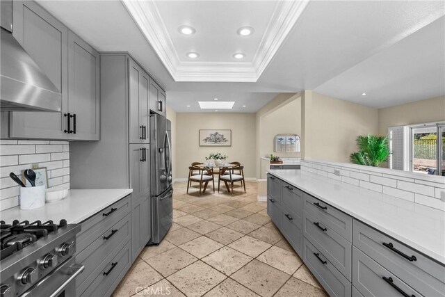3891 Hunters Grove Ct, Moorpark, CA 93021 - kitchen featuring gray cabinetry, wall chimney range hood, ornamental molding, freestanding refrigerator, and light countertops