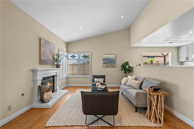 3891 Hunters Grove Ct, Moorpark, CA 93021 - living area featuring light wood-type flooring, plenty of natural light, a glass covered fireplace, lofted ceiling, and recessed lighting