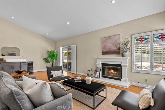 3891 Hunters Grove Ct, Moorpark, CA 93021 - living room with lofted ceiling, light wood-style floors, a glass covered fireplace, wine cooler, and recessed lighting