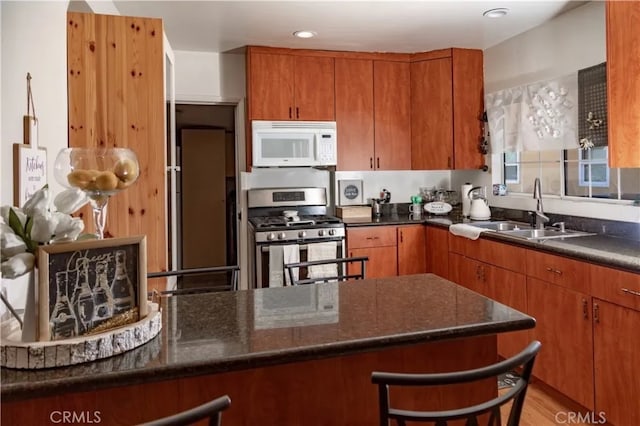 616 E Lomita Ave, Glendale, CA 91205 - kitchen with white microwave, gas range, brown cabinets, dark stone countertops, and a breakfast bar