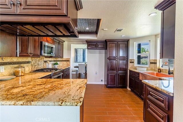 1534 W Summerset Dr, Rialto, CA 92377 - kitchen with appliances with stainless steel finishes, light stone counters, backsplash, a peninsula, and a textured ceiling