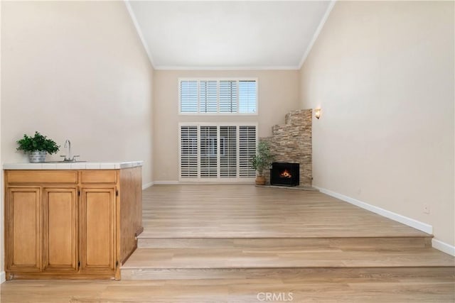 14853 Hartsook St Unit 106, Sherman Oaks, CA 91403 - unfurnished living room with crown molding, light wood-style floors, and a stone fireplace
