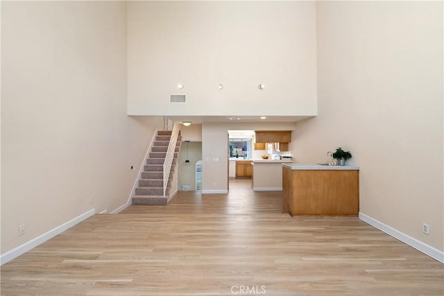 14853 Hartsook St Unit 106, Sherman Oaks, CA 91403 - unfurnished living room featuring stairs, light wood finished floors, and a high ceiling
