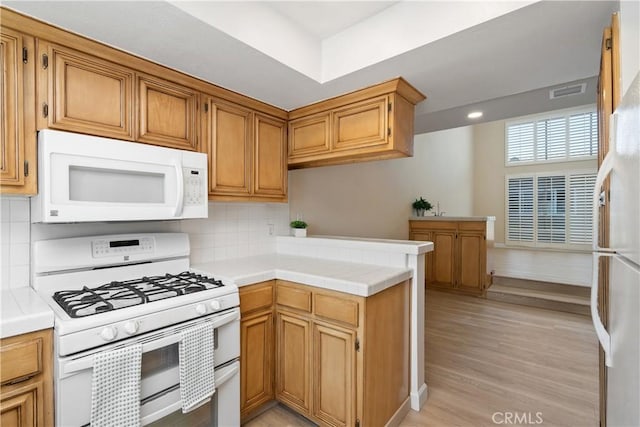 14853 Hartsook St Unit 106, Sherman Oaks, CA 91403 - kitchen featuring white appliances, a peninsula, backsplash, light wood finished floors, and tile counters