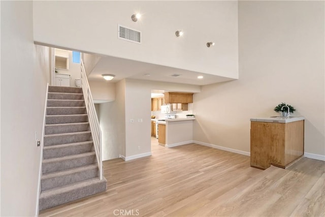 14853 Hartsook St Unit 106, Sherman Oaks, CA 91403 - unfurnished living room featuring stairs, light wood-type flooring, and a high ceiling