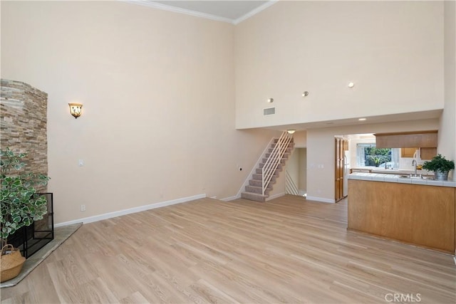 14853 Hartsook St Unit 106, Sherman Oaks, CA 91403 - unfurnished living room with ornamental molding, light wood finished floors, stairway, a high ceiling, and a fireplace