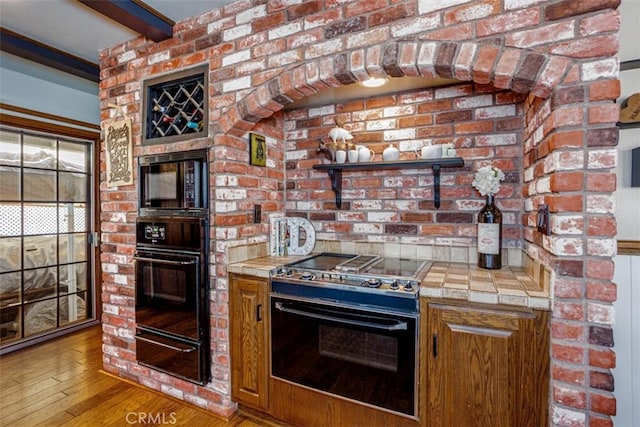 2001 Cypress Point Dr, Corona, CA 92882 - kitchen with black appliances, tile counters, a warming drawer, wood finished floors, and beamed ceiling