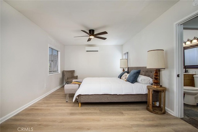 4574 Avenida Del Sol, Joshua Tree, CA 92252 - bedroom with a wall mounted air conditioner, connected bathroom, a ceiling fan, and light wood-style floors