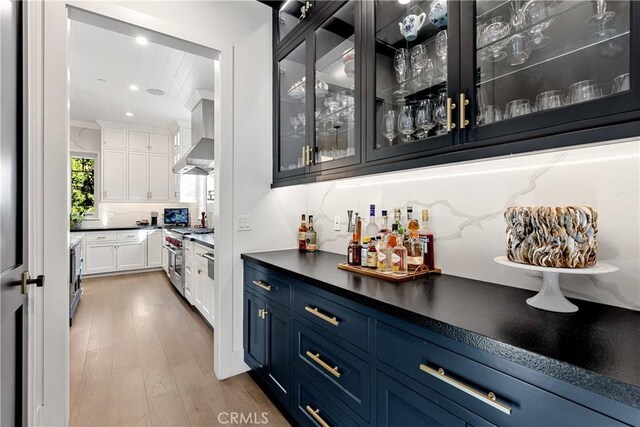 4164 Sunnyslope Ave, Sherman Oaks, CA 91423 - indoor dry bar featuring light wood-style flooring, stainless steel range, tasteful backsplash, wall chimney exhaust hood, and recessed lighting