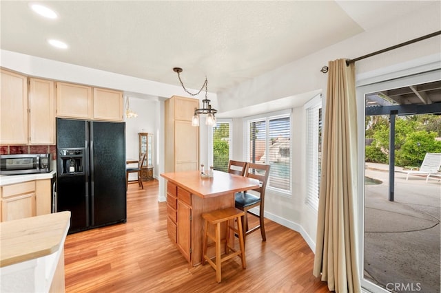 29678 Deal Ct, Temecula, CA 92591 - kitchen with black fridge with ice dispenser, stainless steel microwave, light wood finished floors, healthy amount of natural light, and recessed lighting