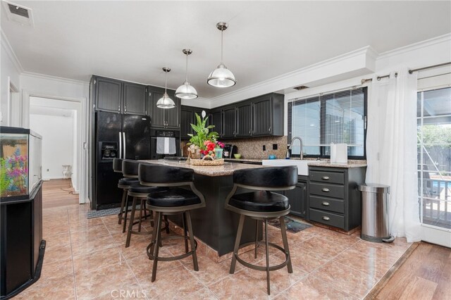 3367 M St, Merced, CA 95348 - kitchen featuring black fridge, crown molding, backsplash, hanging light fixtures, and a breakfast bar area