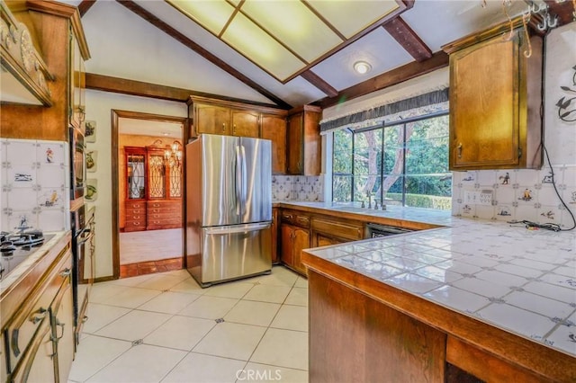 2033 Benbow Pl, Riverside, CA 92506 - kitchen with freestanding refrigerator, decorative backsplash, brown cabinetry, vaulted ceiling, and tile counters