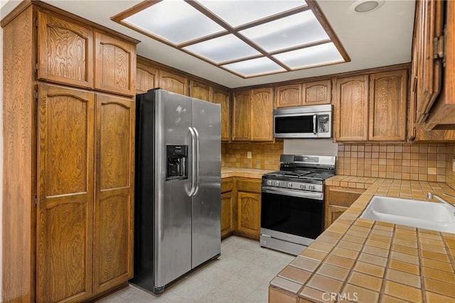 14000 Cerise Ave, Hawthorne, CA 90250 - kitchen featuring stainless steel appliances, tile counters, and brown cabinetry