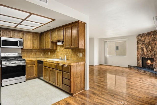 14000 Cerise Ave, Hawthorne, CA 90250 - kitchen with appliances with stainless steel finishes, tile counters, open floor plan, tasteful backsplash, and a stone fireplace