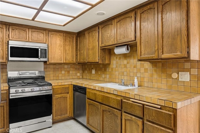 14000 Cerise Ave, Hawthorne, CA 90250 - kitchen featuring stainless steel appliances, tile counters, backsplash, and brown cabinets