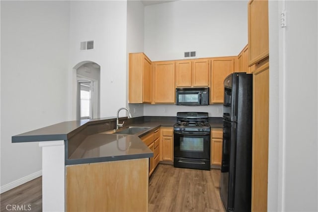 19431 Rue De Valore Unit 5C, Lake Forest, CA 92610 - kitchen with black appliances, a high ceiling, dark countertops, arched walkways, and wood finished floors