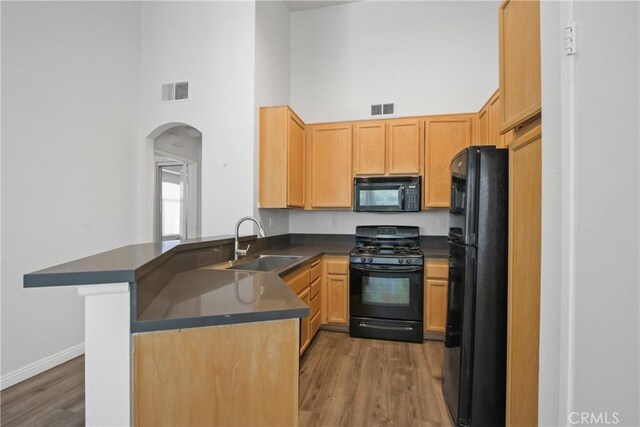 19431 Rue De Valore Unit 5C, Lake Forest, CA 92610 - kitchen with black appliances, a towering ceiling, dark countertops, arched walkways, and wood finished floors