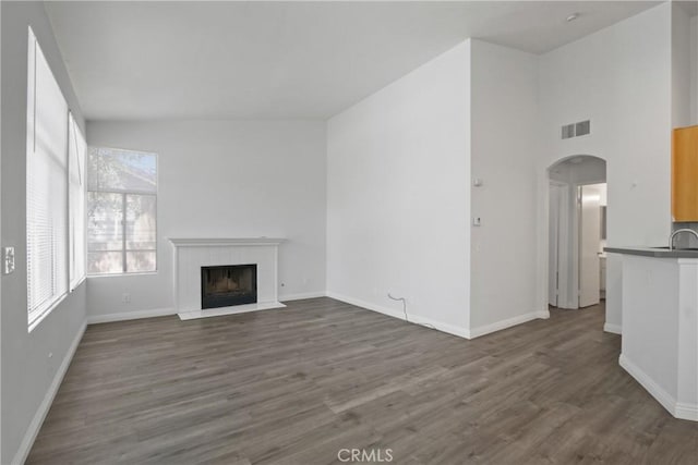 19431 Rue De Valore Unit 5C, Lake Forest, CA 92610 - unfurnished living room featuring a fireplace, dark wood-style flooring, and arched walkways