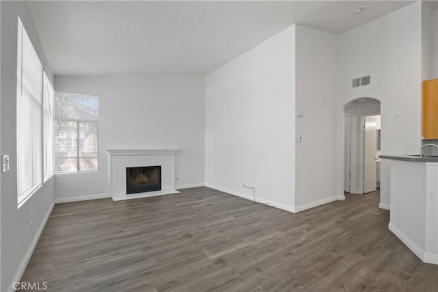 19431 Rue De Valore Unit 5C, Lake Forest, CA 92610 - unfurnished living room featuring a tiled fireplace, dark wood-style flooring, and arched walkways