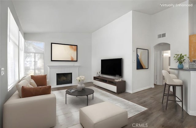 19431 Rue De Valore Unit 5C, Lake Forest, CA 92610 - living room with vaulted ceiling, arched walkways, a fireplace with flush hearth, and wood finished floors