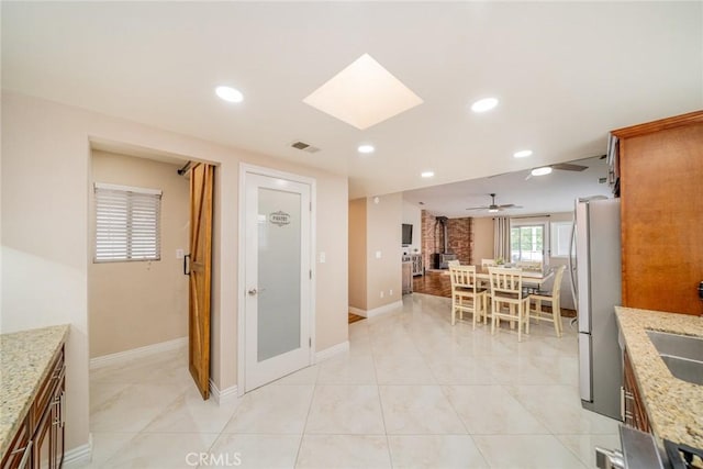 18210 Deauville Dr, Victorville, CA 92395 - kitchen featuring recessed lighting, freestanding refrigerator, light stone countertops, ceiling fan, and a skylight